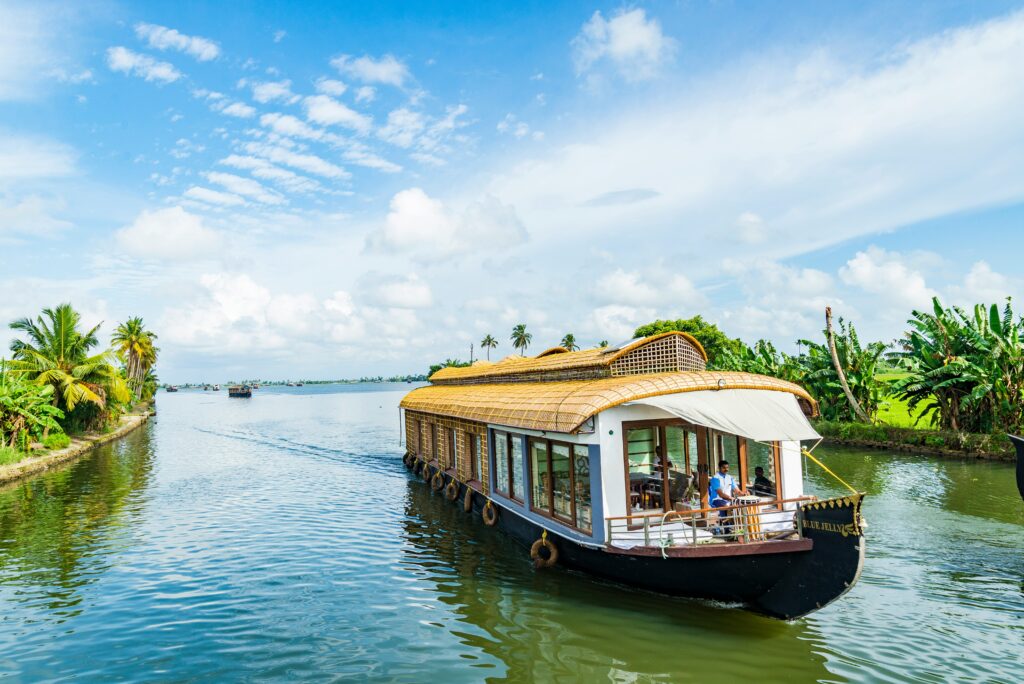 Traditional houseboat cruising through Kerala backwaters surrounded by lush greenery